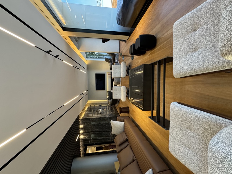 A living room with linear ceiling lights, floor-level illumination and a wall-mounted television.