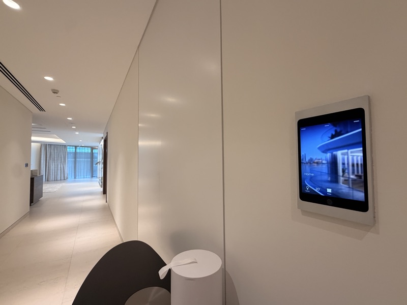 A wall-mounted home interface beside the hallway and living spaces.