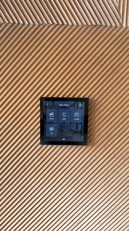 A wall-mounted touchscreen with dedicated scene, lighting, curtain and AC controls.